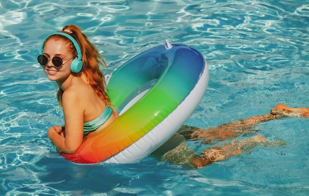 Jeune femme d'été profitant d'une femme bronzée en maillot de bain sur un cercle gonflable dans la piscine