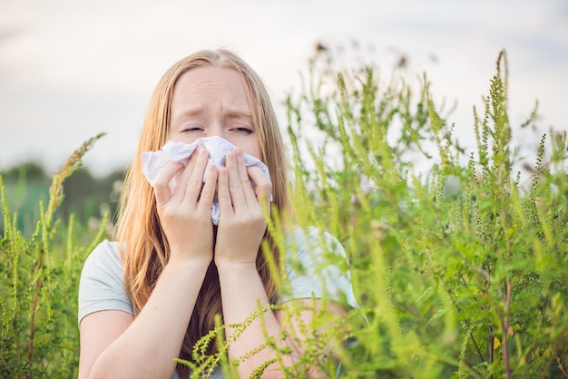 Une jeune femme éternue à cause d'une allergie à l'ambroisie