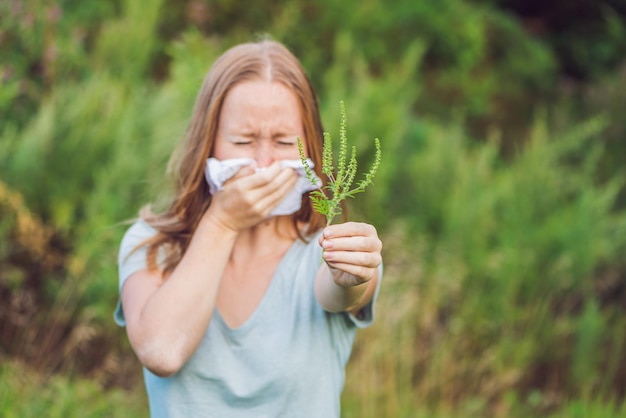 Une jeune femme éternue à cause d'une allergie à l'ambroisie