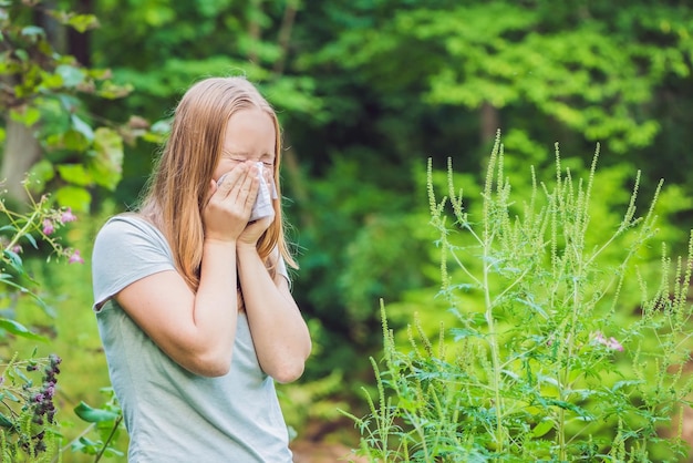 Une jeune femme éternue à cause d'une allergie à l'ambroisie