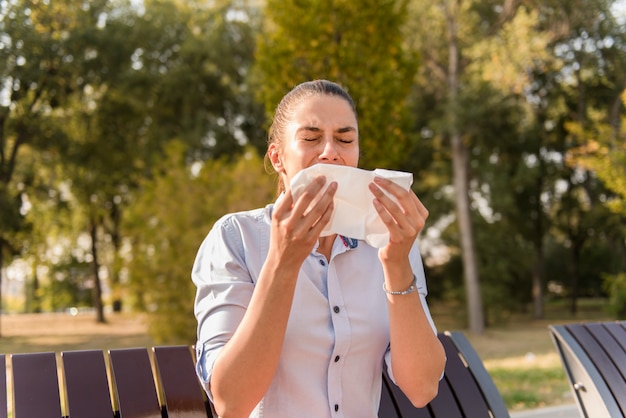 Jeune femme éternuer tout en ayant une allergie