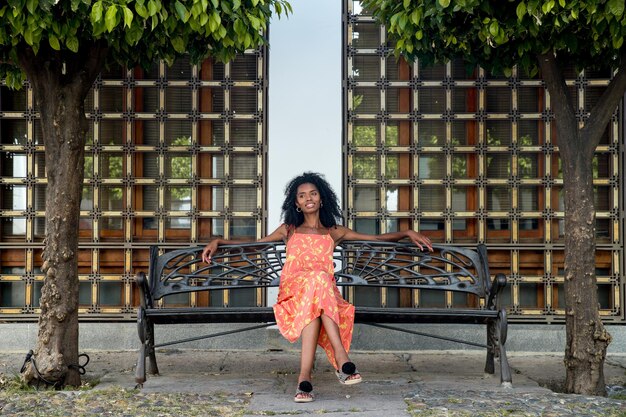 Jeune femme ethnique assise sur un banc dans le parc