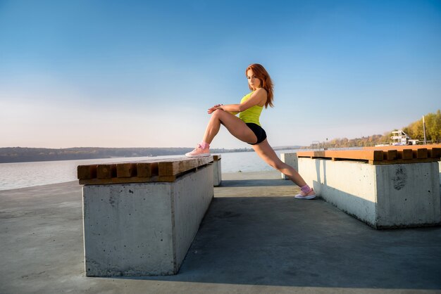 Jeune femme étirant les jambes tôt le matin avant le temps de travail à l'extérieur.