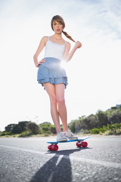 Jeune femme étonnée en équilibre sur sa planche à roulettes