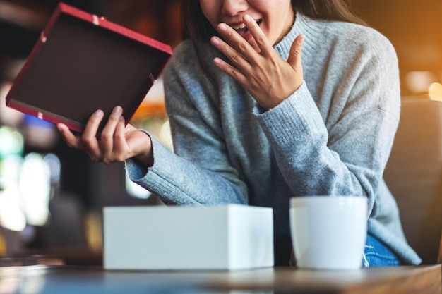 Jeune femme étonnée ouvrant une boîte-cadeau