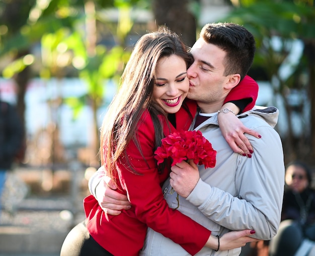 Jeune femme étreignant son petit ami parce qu'il lui a donné des fleurs - Concept de la Saint-Valentin