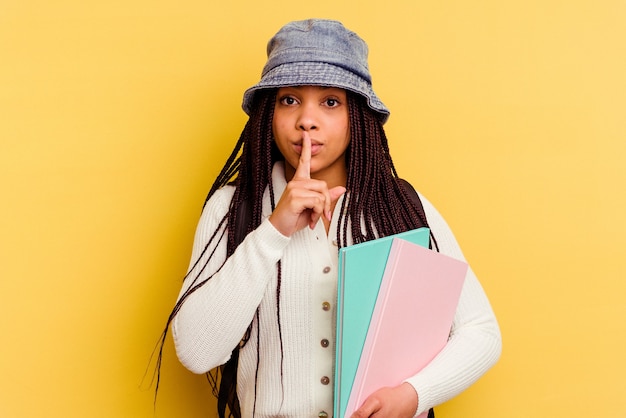 Jeune Femme étudiante Afro-américaine Isolée Sur Fond Jaune Gardant Un Secret Ou Demandant Le Silence.