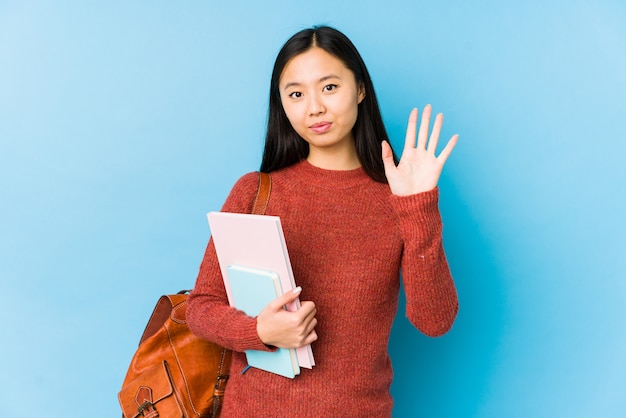 Jeune femme étudiante asiatique souriant joyeux montrant le numéro cinq avec les doigts