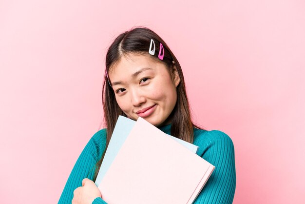 Jeune femme étudiante asiatique tenant des livres isolés sur fond rose