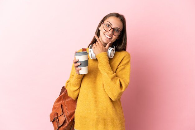 Jeune femme étudiante sur fond rose isolé heureux et souriant