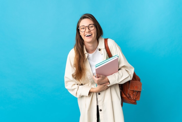 Jeune femme étudiante sur mur isolé souriant beaucoup