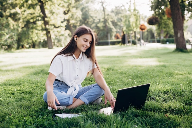 Jeune femme étudiante avec ordinateur portable dans le parc