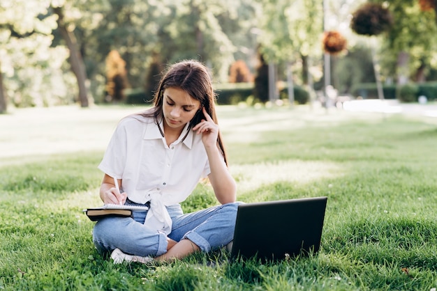 Jeune femme étudiante avec ordinateur portable dans le parc