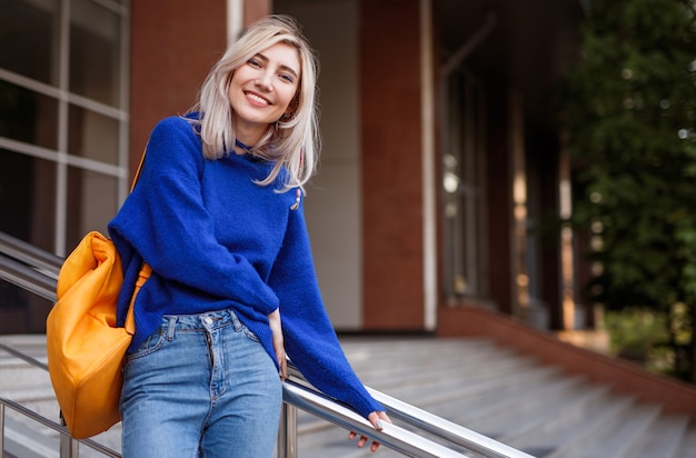 Jeune femme étudiante souriante sur les marches de l'université