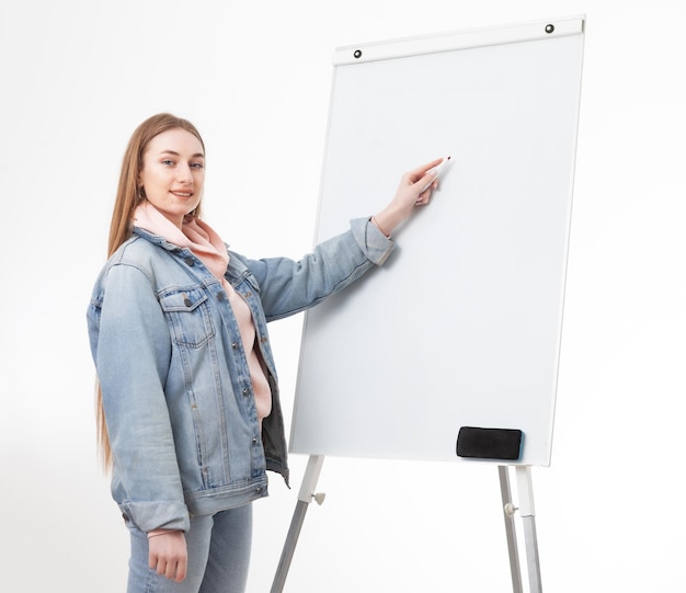 Jeune femme étudiante en vêtements denim écrit avec un marqueur sur un tableau blanc Concept de l'éducation