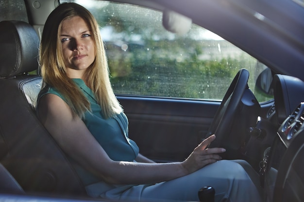 Jeune femme européenne aux cheveux blonds conduit une voiture