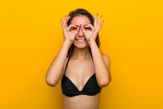 Jeune femme européenne en bikini montrant un signe correct sur ses yeux