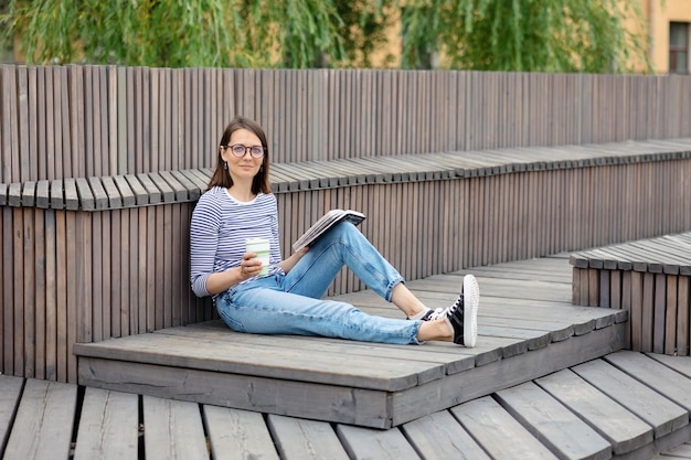 Une jeune femme européenne confiante se repose et lit un livre une femme boit du café se détend ou