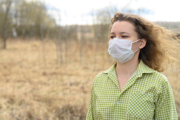 jeune femme européenne dans un masque médical sur son visage dans la nature en plein air. concept de protection du coronavirus covid-19