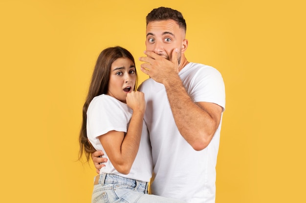 Une jeune femme européenne effrayée et choquée et un gars en casual avec la bouche ouverte pressent les mains vers le visage.