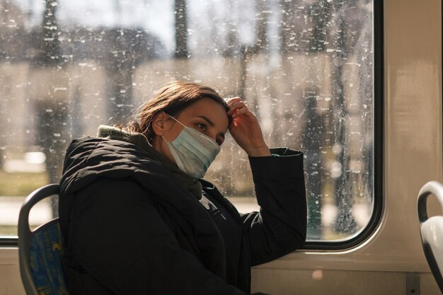 Jeune femme européenne avec masque médical dans les transports urbains