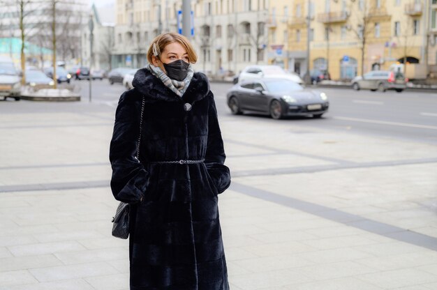 Jeune femme européenne en masque noir médical jetable de protection en ville en plein air. protection du concept de dangereux 2019-nCoV