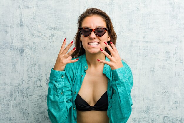 Jeune femme européenne portant un bikini bouleversé criant avec des mains tendues.