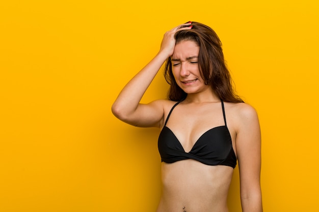 Jeune femme européenne portant un bikini en oubliant quelque chose, en frappant le front avec la paume et en fermant les yeux.