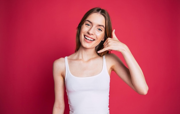 Jeune femme excitée et heureuse avec un visage surpris regarde la caméra sur le mur rose