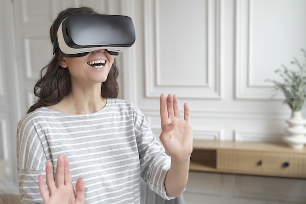 Jeune femme excitée portant un casque vr interagissant avec le monde augmenté jouant à des jeux à la maison