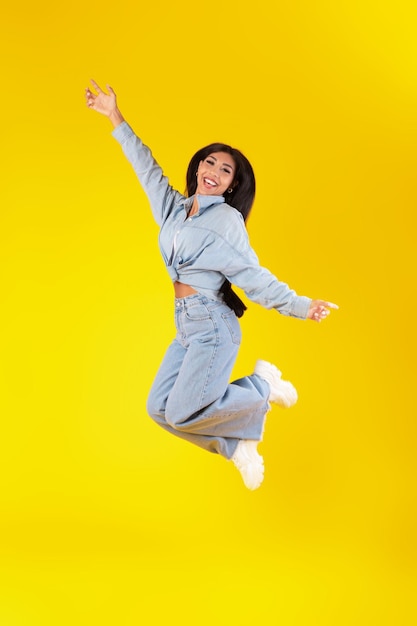 Jeune femme excitée sautant au studio orange