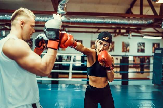 Jeune femme exerçant avec un entraîneur à la leçon de boxe et d'autodéfense.