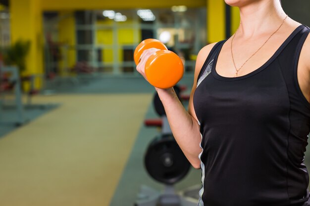 Jeune femme exerçant avec des poids dans la salle de gym