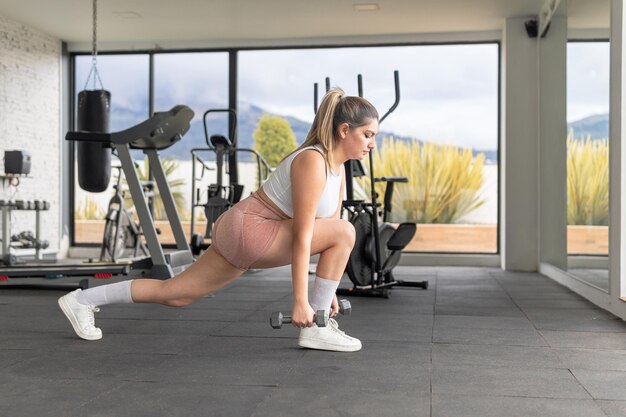 Photo une jeune femme exerce ses jambes avec des haltères dans un gymnase.