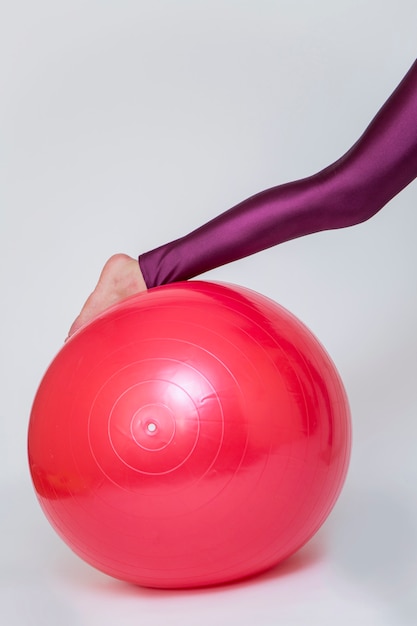 Jeune femme exercice avec ballon de pilates rouge isolé sur blanc