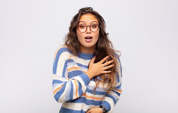 jeune femme expressive avec des lunettes posant sur un mur blanc