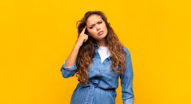 jeune femme expressive posant sur un mur jaune