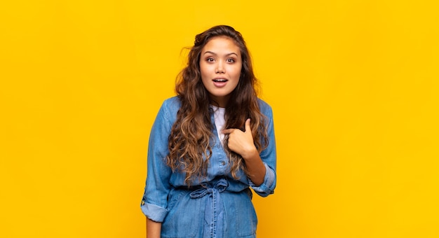 jeune femme expressive posant sur un mur jaune