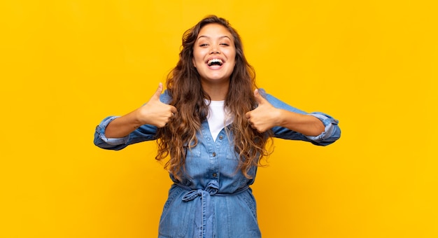 jeune femme expressive posant sur un mur jaune