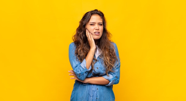 jeune femme expressive posant sur un mur jaune