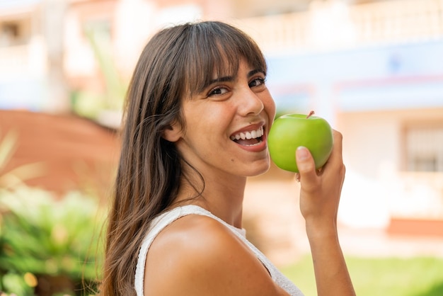 Jeune femme à l'extérieur mangeant une pomme