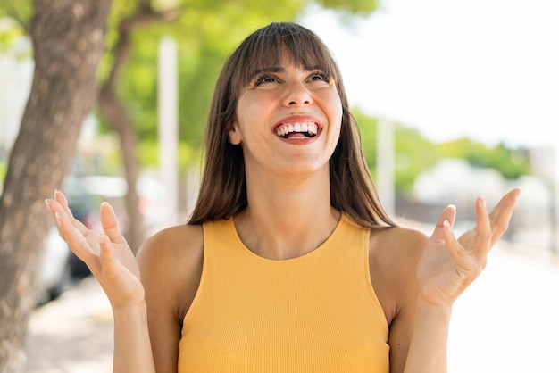 Jeune femme à l'extérieur souriant beaucoup