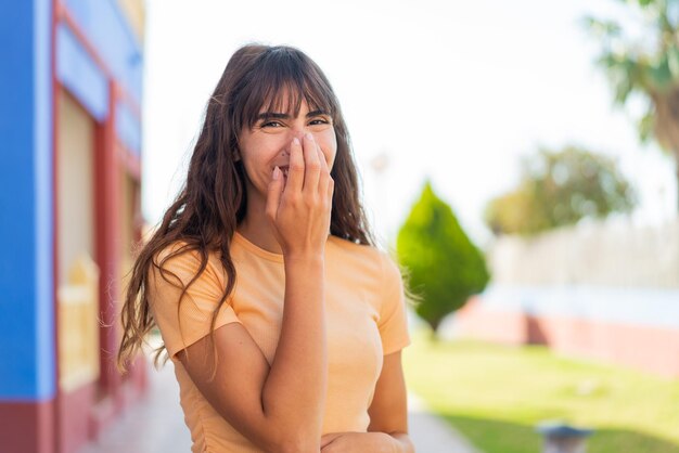 Jeune femme à l'extérieur souriant beaucoup