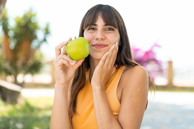 Une jeune femme à l'extérieur tenant une pomme