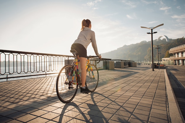 Jeune femme, faire du vélo dans la ville du matin