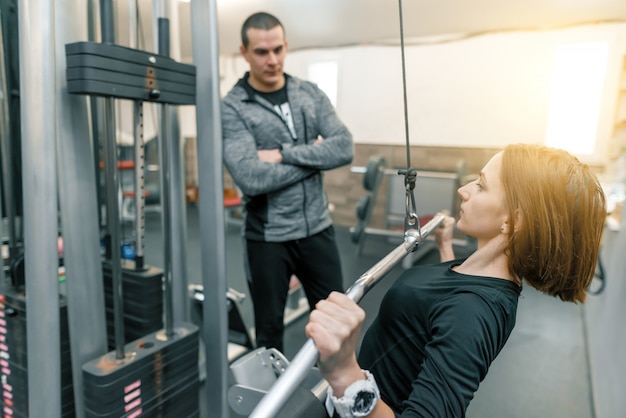 Jeune femme, faire, exercices, à, instructeur personnel, dans, gymnase