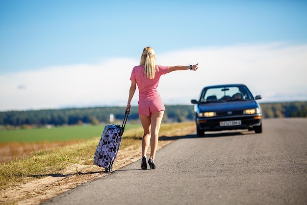 Jeune femme faisant de l'auto-stop sur une route dans les champs