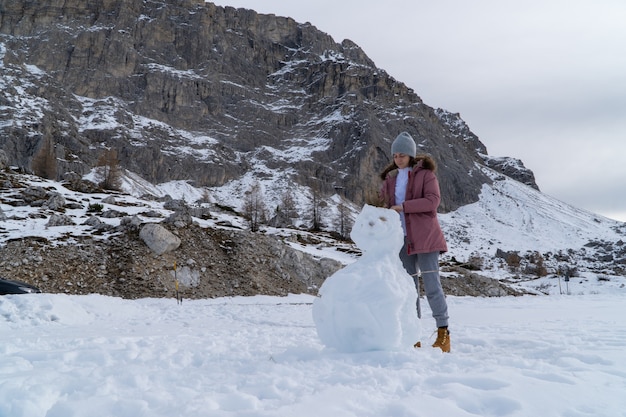 Jeune femme faisant un bonhomme de neige sur une montagne