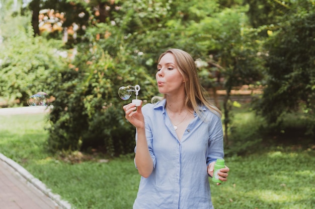 Jeune femme faisant des bulles dans le parc et s'amusant