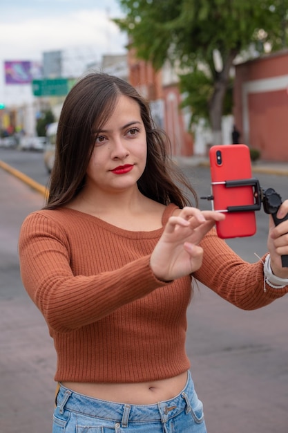 Jeune femme faisant du vlog vidéo avec smartphone et stabilisateur de cardan en plein air, vlogging dans les rues